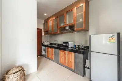 a kitchen with wooden cabinets and a white refrigerator at Little Kamala Hill in Kamala Beach