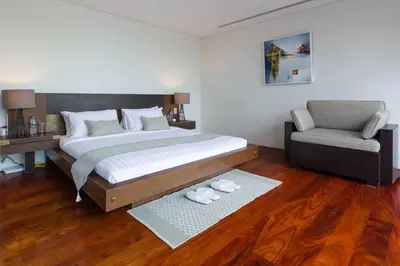 a bedroom with a large bed and a chair at 28 - Sea View Luxury Pool Villa in Phuket Town