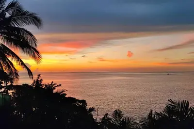 a sunset over the ocean with a palm tree at 28 - Sea View Luxury Pool Villa in Phuket Town