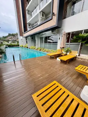 a building with a swimming pool and yellow benches at Chic Condominium Karon B511 in Karon Beach