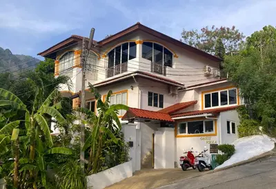 a house with a motorcycle parked in front of it at BOUTIQUE-VILLA with Suites & Rooms in Karon Beach