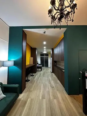 a living room with a green wall and a chandelier at Chill-long inn in Ban Klang