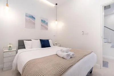 a white bedroom with a bed with a towel on it at Seven Heaven Patong Villa in Patong Beach
