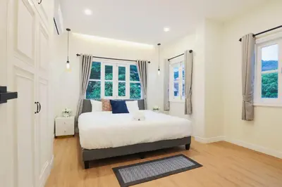 a bedroom with a bed and two windows at Seven Heaven Patong Villa in Patong Beach
