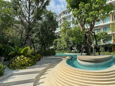 a swimming pool with trees and a building at Phyll Phuket - Luxury Resort-Style Comfort in Ban Rangeng