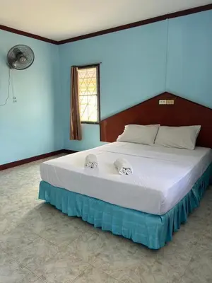 a large bed in a bedroom with a blue wall at อดัมบังกะโล in Ao Nang Beach