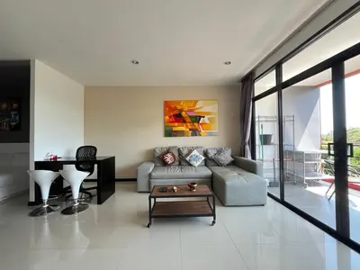a living room with a couch and a table at Stunning 60 sqm Studio at NaiHarn Beach Condo, Walk to Beach, Your Tropical Retreat! in Rawai Beach
