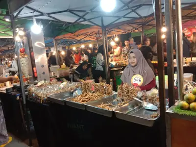 a woman standing in front of a food stand at a market at Zcape Condotel Bangtao Beach in Bang Tao Beach
