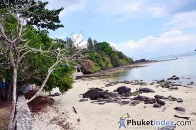 a beach with trees and rocks in the water at thechalethome in Panwa Beach