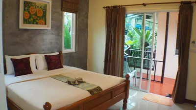 a bedroom with a bed and a sliding glass door at Pennapa Chalet in Chalong