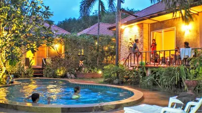 a pool in front of a house with people in it at Pennapa Chalet in Chalong