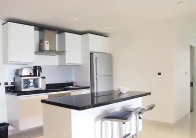a kitchen with white cabinets and a black counter top at Nakalay Palm by Thaire in Kamala Beach