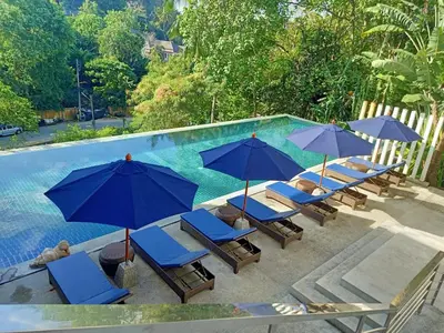 a group of chairs and umbrellas next to a swimming pool at Karon Beach Residence in Karon Beach