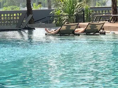 two people laying in chairs in a swimming pool at Junior Suite D37 Kamala Beach in Kamala Beach