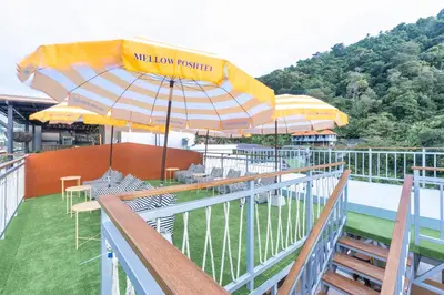 a patio with tables and umbrellas on a deck at Mellow Poshtel - Kata Beach in Kata Beach