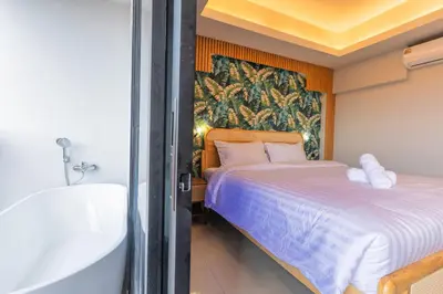 a bedroom with a bed and a bath tub next to a bath tub at Mellow Poshtel - Kata Beach in Kata Beach