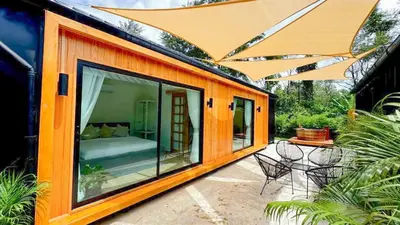 a house with a large glass window and a bed at Sea Salt Casa Bang Tao in Ban Thalat Choeng Thale