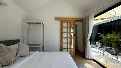 a bedroom with a bed and a balcony at Sea Salt Casa Bang Tao in Ban Thalat Choeng Thale