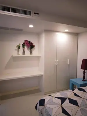 a room with a bed and a shelf with flowers at Karon Beach Large 2 bedrooms & living room Seaview apartment in Karon Beach
