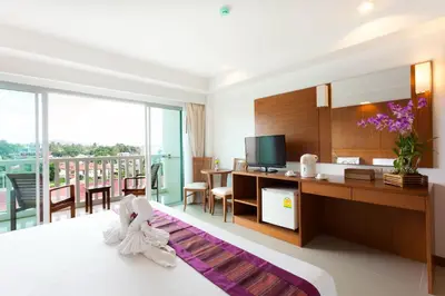 a hotel room with a bed and a desk and a television at Rawai Princess Hotel in Rawai Beach