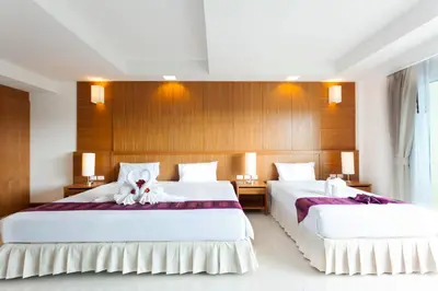 two beds in a hotel room with white sheets at Rawai Princess Hotel in Rawai Beach