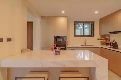 a kitchen with a large white counter and chairs at ANDAMAN Villa KOH YAO NOI in Ko Yao Noi