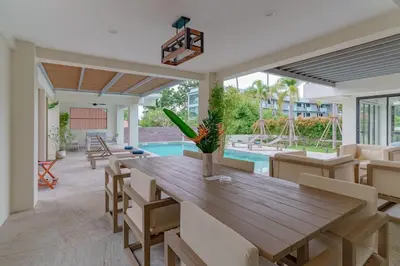 a dining room with a wooden table and chairs and a pool at ANDAMAN Villa KOH YAO NOI in Ko Yao Noi