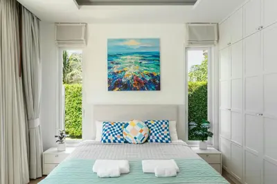 a bedroom with a bed and a painting on the wall at Friendly Kamala Garden View in Kamala Beach