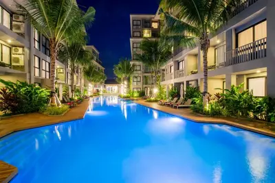 a pool at night with palm trees and buildings at Apartment 2 BDR Bangtao #2206 in Phuket