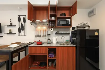 a kitchen with wooden cabinets and a black refrigerator at Studio 777 condo MaiKhao in Phuket Town
