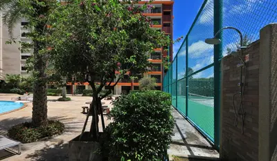 a swimming pool with a tree and a building at Studio 777 condo MaiKhao in Phuket Town