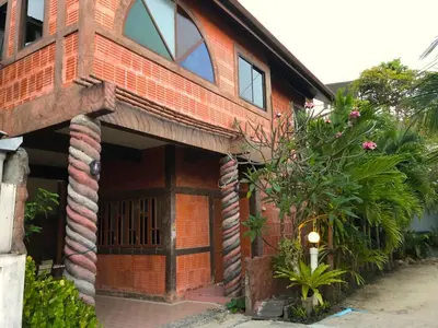 a red brick house with a large door at Kamala beach house 100m to the beach in Kamala Beach