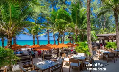 a restaurant with tables and umbrellas on the beach at Kamala beach house 100m to the beach in Kamala Beach