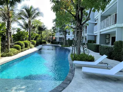 a swimming pool in front of a building with two white chairs at Private apartment Title V Condo by Lofty in Rawai Beach