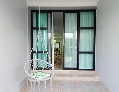 a white swinging chair in front of a house at Calm & Cozy Vacation House in Rawai Beach