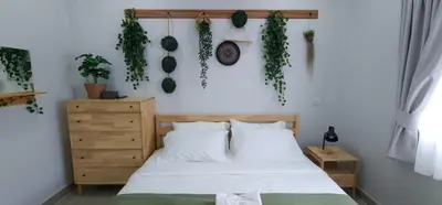 a bedroom with a bed and plants on the wall at Calm & Cozy Vacation House in Rawai Beach
