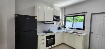 a kitchen with white cabinets and a black refrigerator at Calm & Cozy Vacation House in Rawai Beach