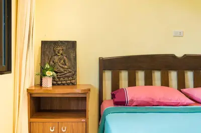 a bedroom with a bed and a statue of a buddha at Baan Coconut in Bang Tao Beach