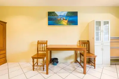 a dining room table with two chairs and a painting on the wall at Baan Coconut in Bang Tao Beach