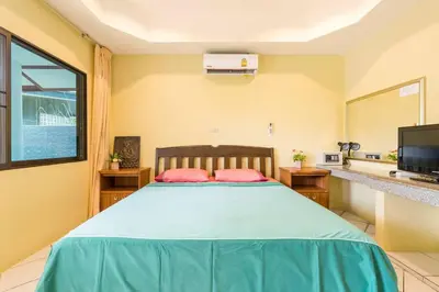 a bedroom with a large bed and a large window at Baan Coconut in Bang Tao Beach