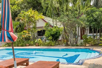 a swimming pool with an umbrella next to a house at Baan Coconut in Bang Tao Beach