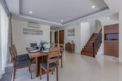 a dining room with a table and chairs and a staircase at Laguna Parkside by Triple8 Asia in Laguna Phuket