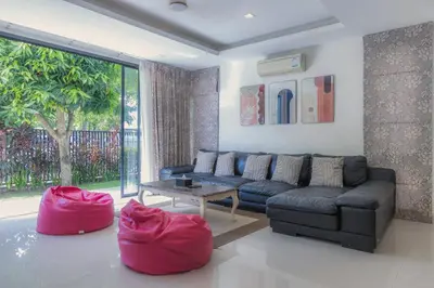 a living room with a couch and red ottoman at Laguna Parkside by Triple8 Asia in Laguna Phuket