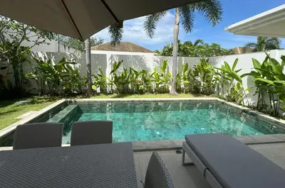 a swimming pool with chairs and an umbrella at Trichada Tropical pool villa by Lofty in Bang Tao Beach