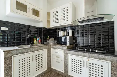 a kitchen with white cabinets and black tiles at Pool Villa 3 Bedrooms, Closeby Patong, Chic and Quiet in Kathu