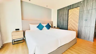 a bedroom with a large white bed with blue pillows at Luxury studio near Nai Harn beach in Rawai Beach