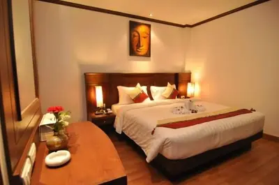a bedroom with a large white bed and a table at Hemingway's Hotel in Patong Beach