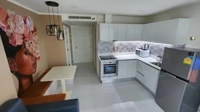 a kitchen with white appliances and a painting of a woman at Karon Butterfly Residence in Kata Beach
