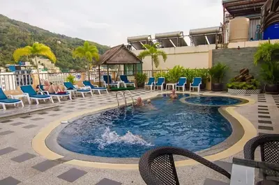 a pool at a hotel with chairs and people in it at Patong Hemingways Hotel in Patong Beach