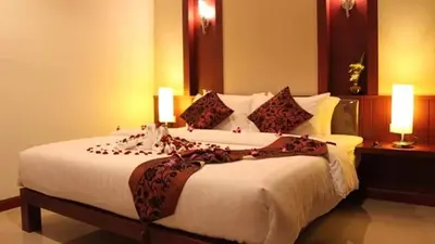a bedroom with a large bed with two lamps on it at Patong Hemingways Hotel in Patong Beach